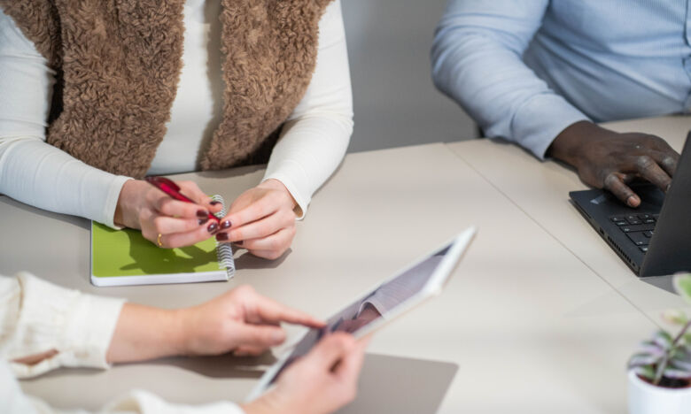 Personen in an einem Tisch mit Laptop und Tablet