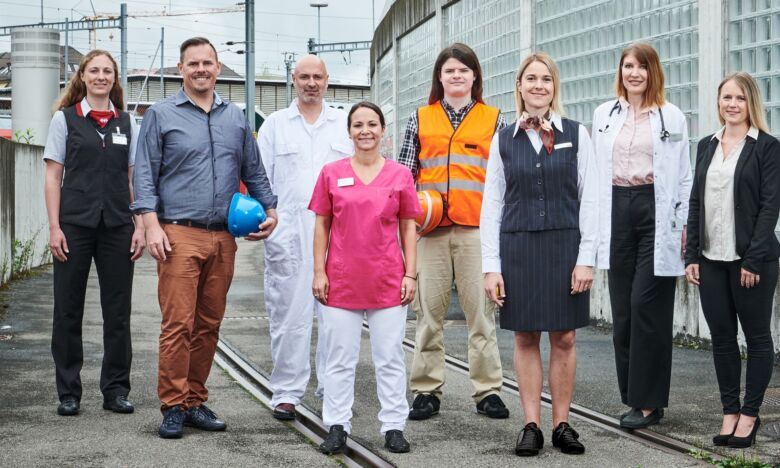 Personen aus verschiedenen Berufskategorien stehen draussen zusammen
