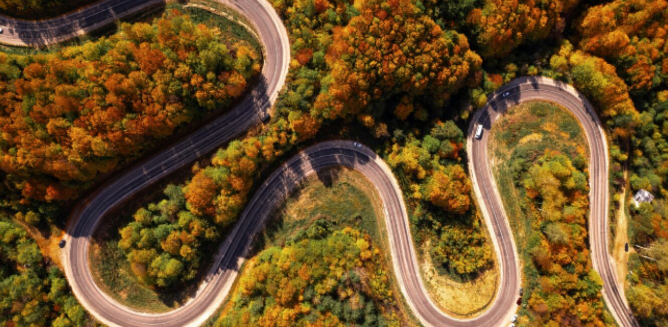 Luftaufnahme einer kurvigen Straße durch den Herbstwald