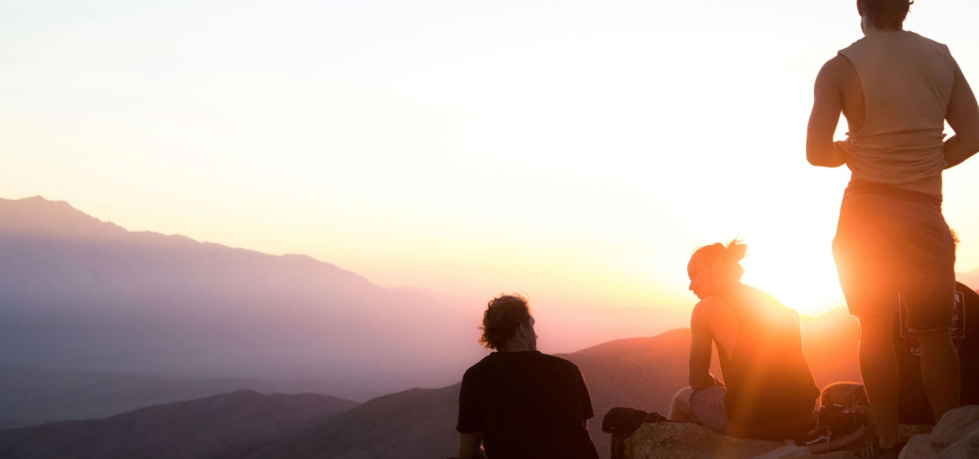 Menschen sitzen bei Sonnenuntergang auf Berg