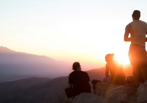 Menschen sitzen bei Sonnenuntergang auf Berg