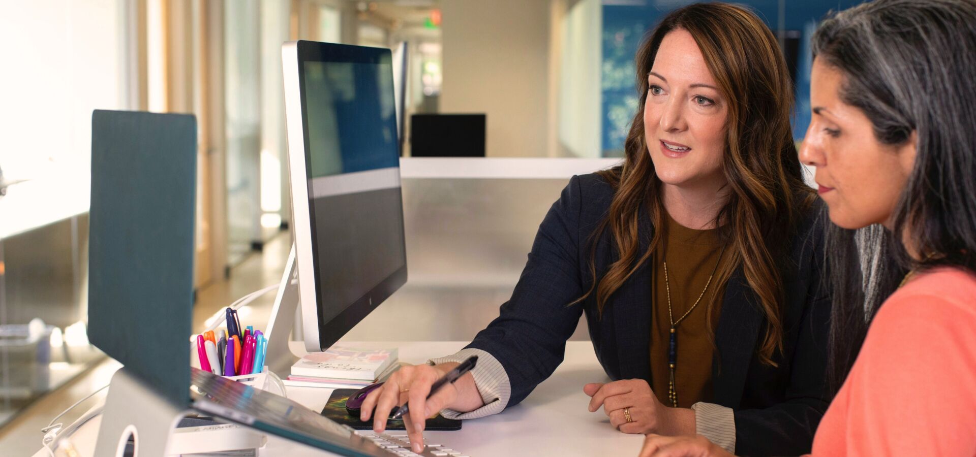 Zwei Frauen im Büro schauen sich etwas am Laptop an