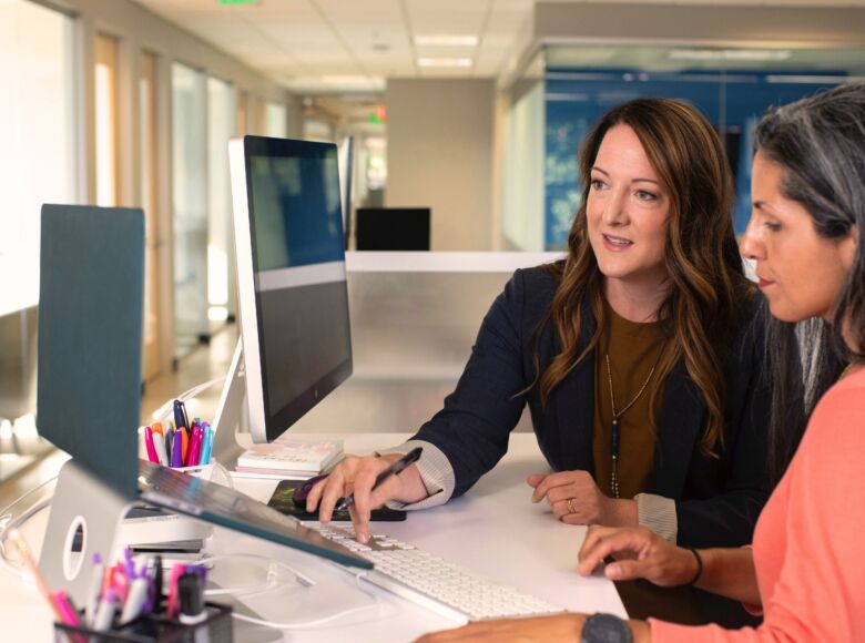 Zwei Frauen im Büro schauen sich etwas am Laptop an